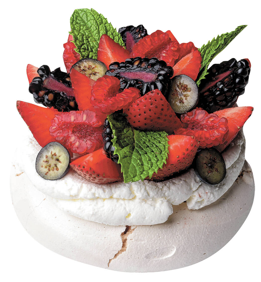 Pavlova, a crunchy meringue with a soft center, topped with fresh berries, berry dust, and mint ...