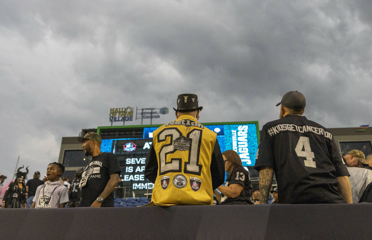Raiders fans look to the sky during a severe weather alert that delayed the start of the NFL Ha ...