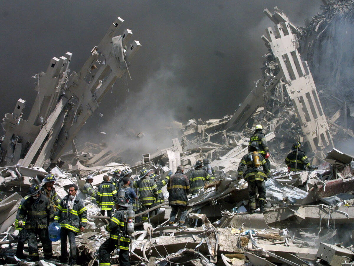 FILE - Firefighters make their way through the rubble after two airliners crashed into the Worl ...