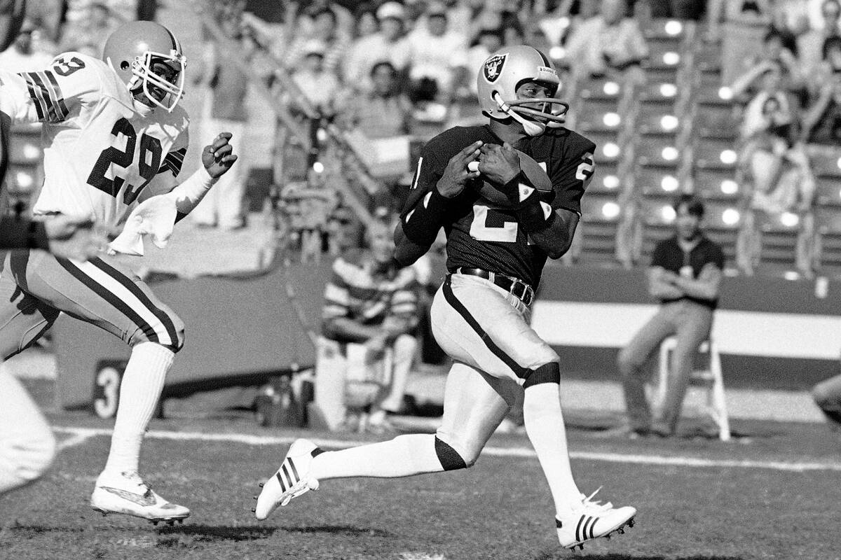 Los Angeles Raiders wide receiver Cliff Branch, right, catches a pass from quarterback Jim Plun ...