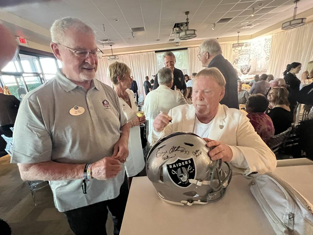Raiders owner Mark Davis signs a helmet for ex-Raiders great Dave Casper at the Raiders' party ...