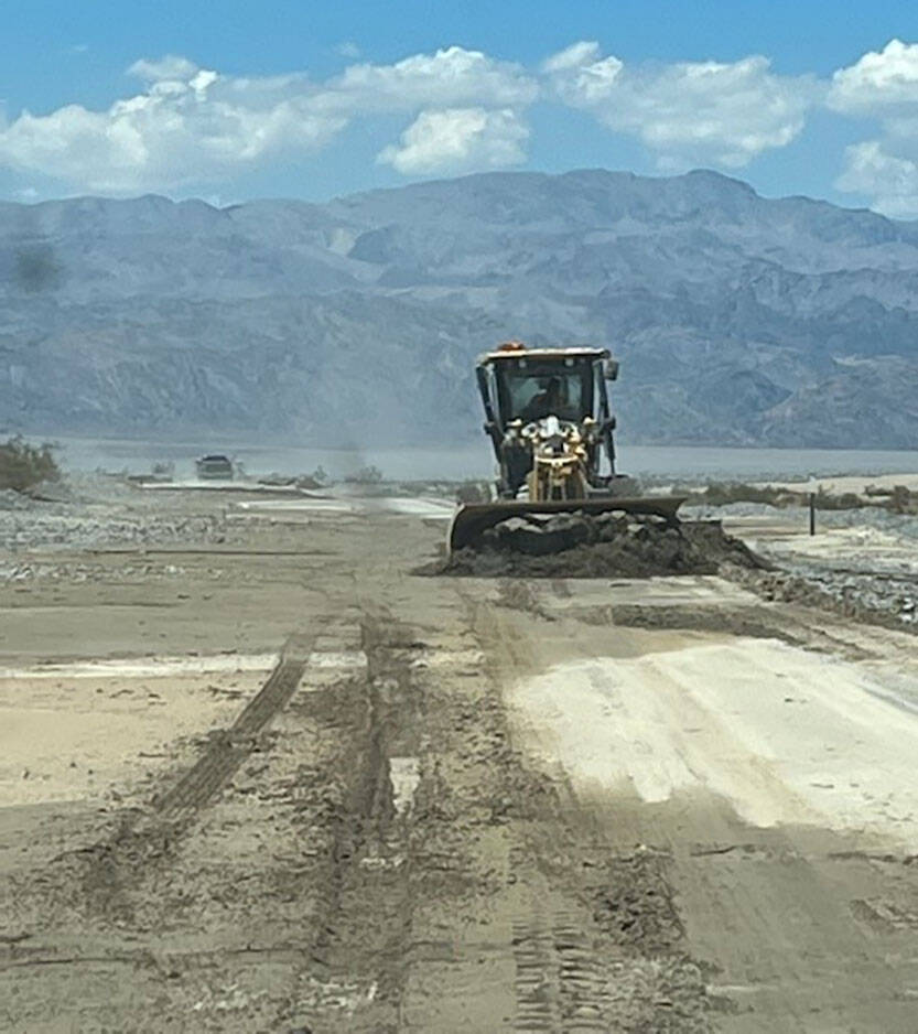 A bulldozer works to remove mud on California Route 190 after historic flooding at Death Valley ...