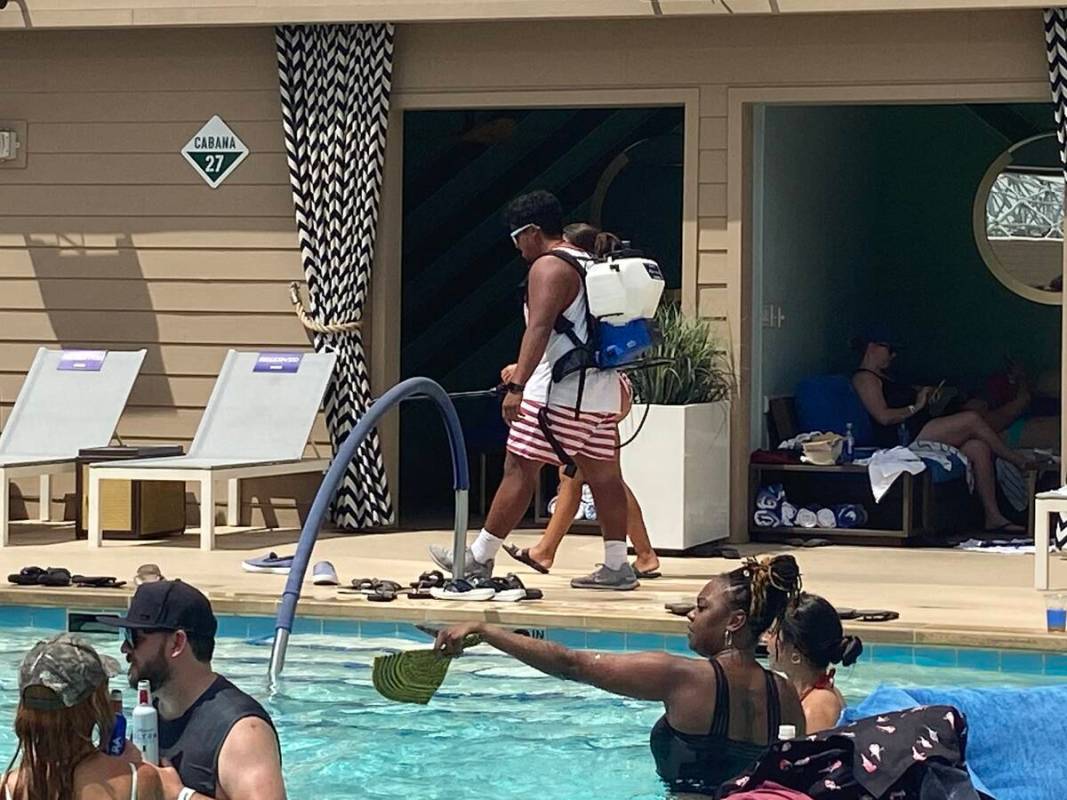 A lifeguard with a tank of cool water roams Circa Resort's Stadium Swim on July 22, 2022, spray ...