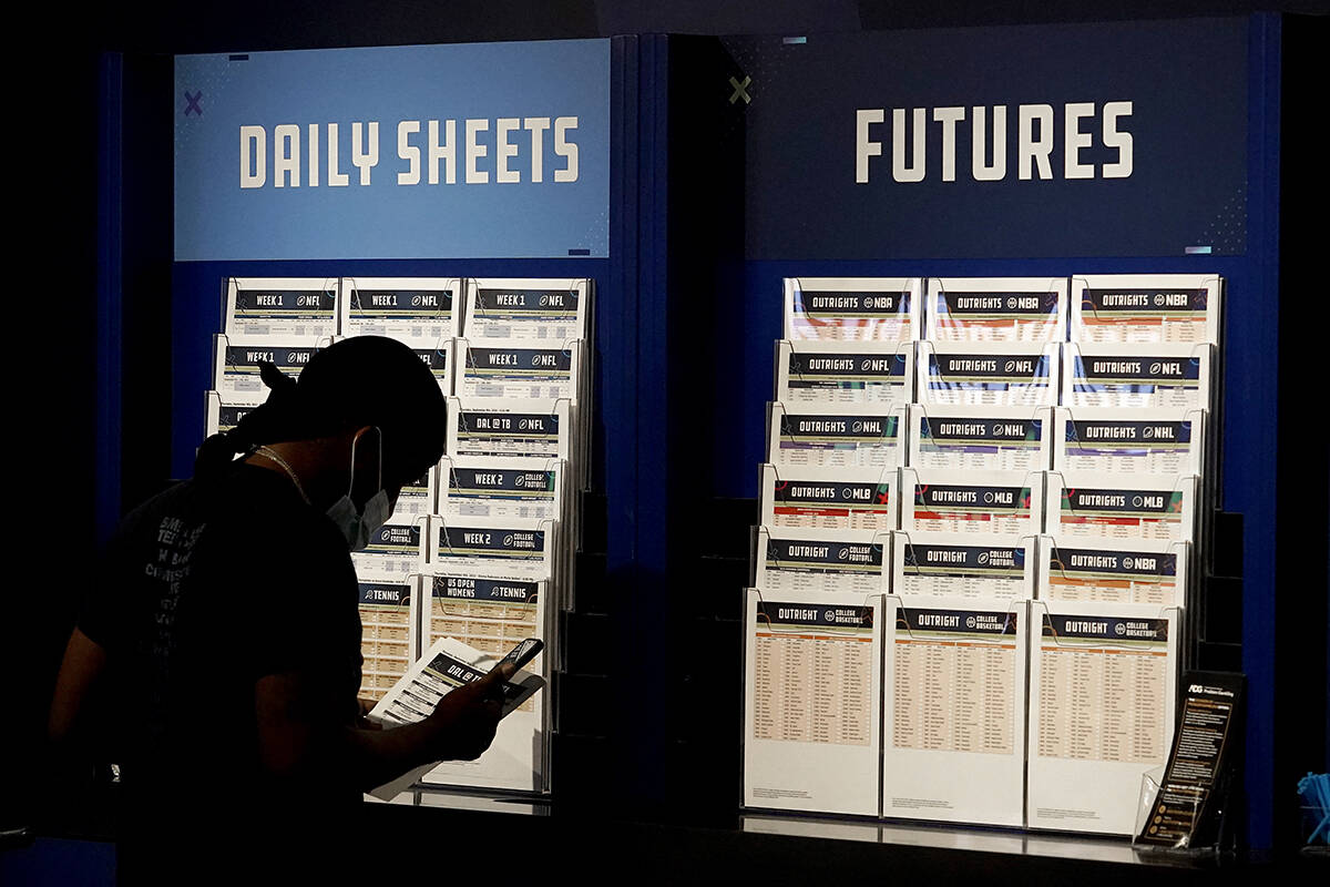 A customer looks over daily sheets inside FanDuel Sportsbook inside Footprint Center, Thursday, ...