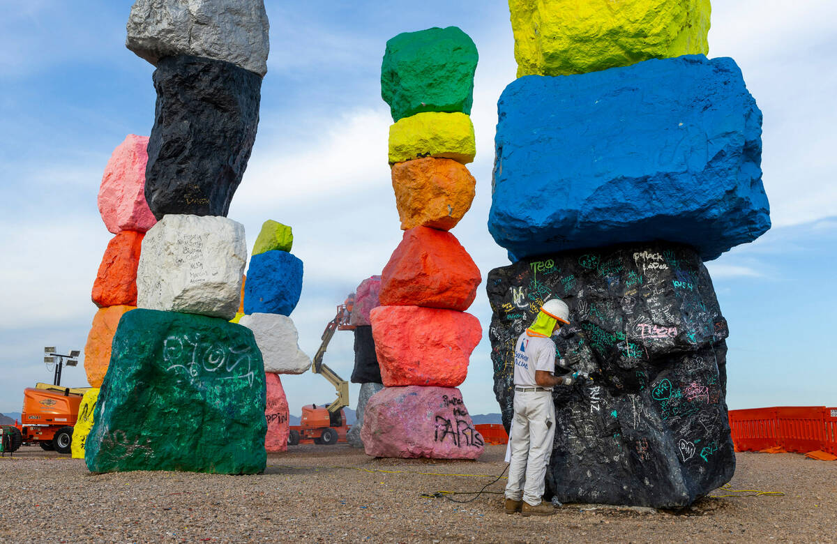 Journeyman Painter Paul Davis grinds graffiti off base stones at Seven Magic Mountains as the a ...