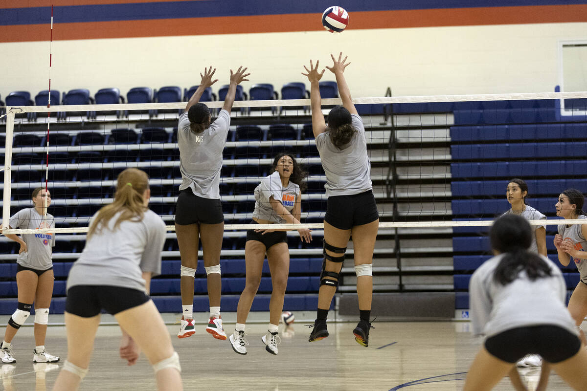 Bishop Gorman’s Leilia Toailoa, center, spikes across the net while teammates jump to bl ...