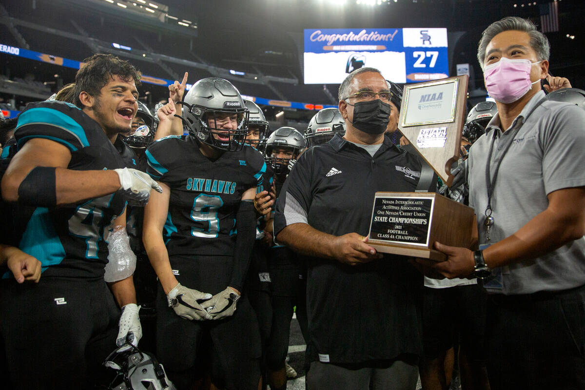 Silverado head coach Alejandro Ostolaza accepts Class 4A football state championship trophy aft ...