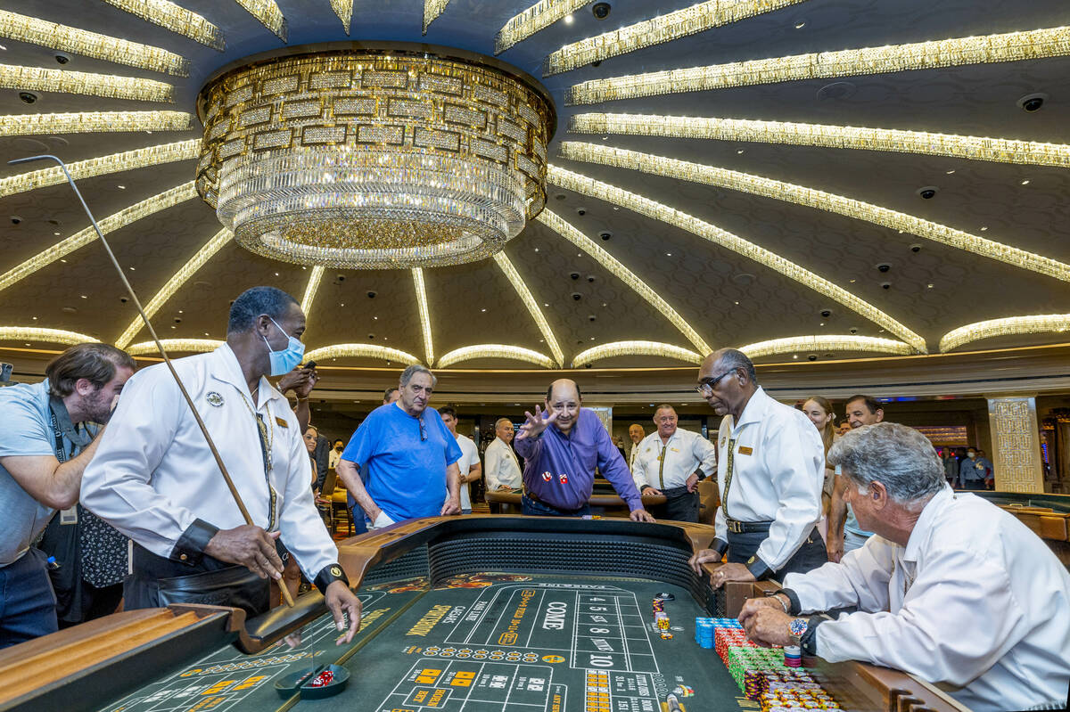 Gambler Juan Fresquez Jr., of Texas, center, tosses the first dice in craps at Caesars as they ...