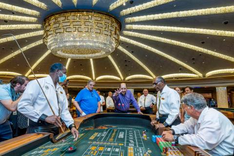 Gambler Juan Fresquez Jr., of Texas, center, tosses the first dice in craps at Caesars as they ...