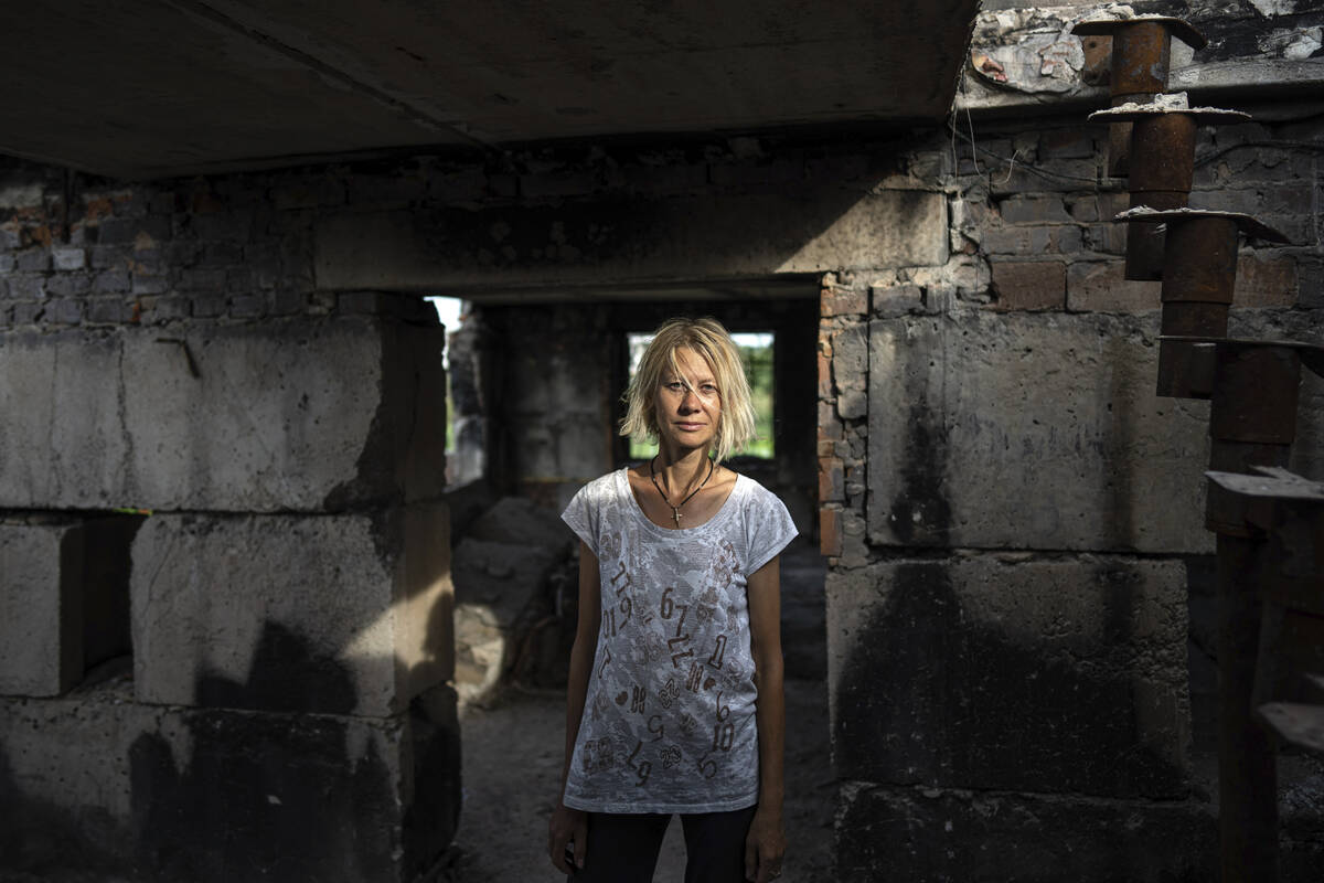 Zhanna Dynaeva stands inside her house which was destroyed by Russian bombardment, in the vill ...