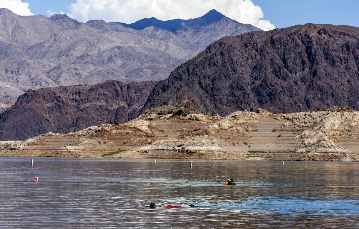 Search and rescue personnel dive near the shoreline as authorities are assessing what were desc ...