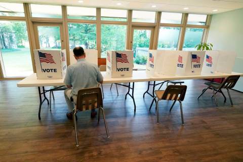 A voter sits alone at a poll kiosk to cast his vote at a Mississippi Second Congressional Distr ...