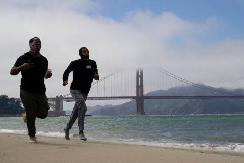 John Chappell, left, and his brother Chris run on Golden Gate Beach in San Francisco, Tuesday, ...
