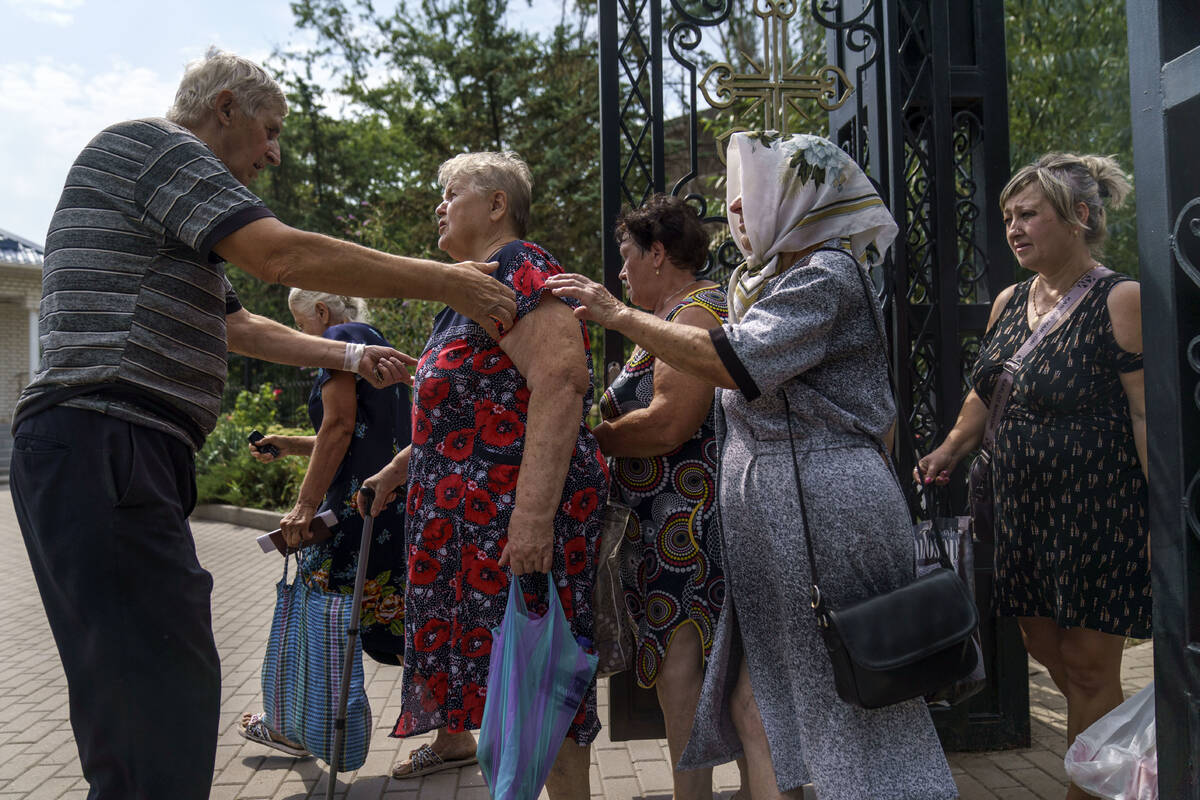 A church worker controls a crowd of local residents waiting to receive humanitarian aid at Sain ...