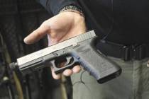 Matt Supnick holds a Glock semi-automatic pistol to explain the difference between a semi-autom ...