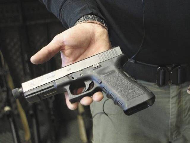 Matt Supnick holds a Glock semi-automatic pistol to explain the difference between a semi-autom ...