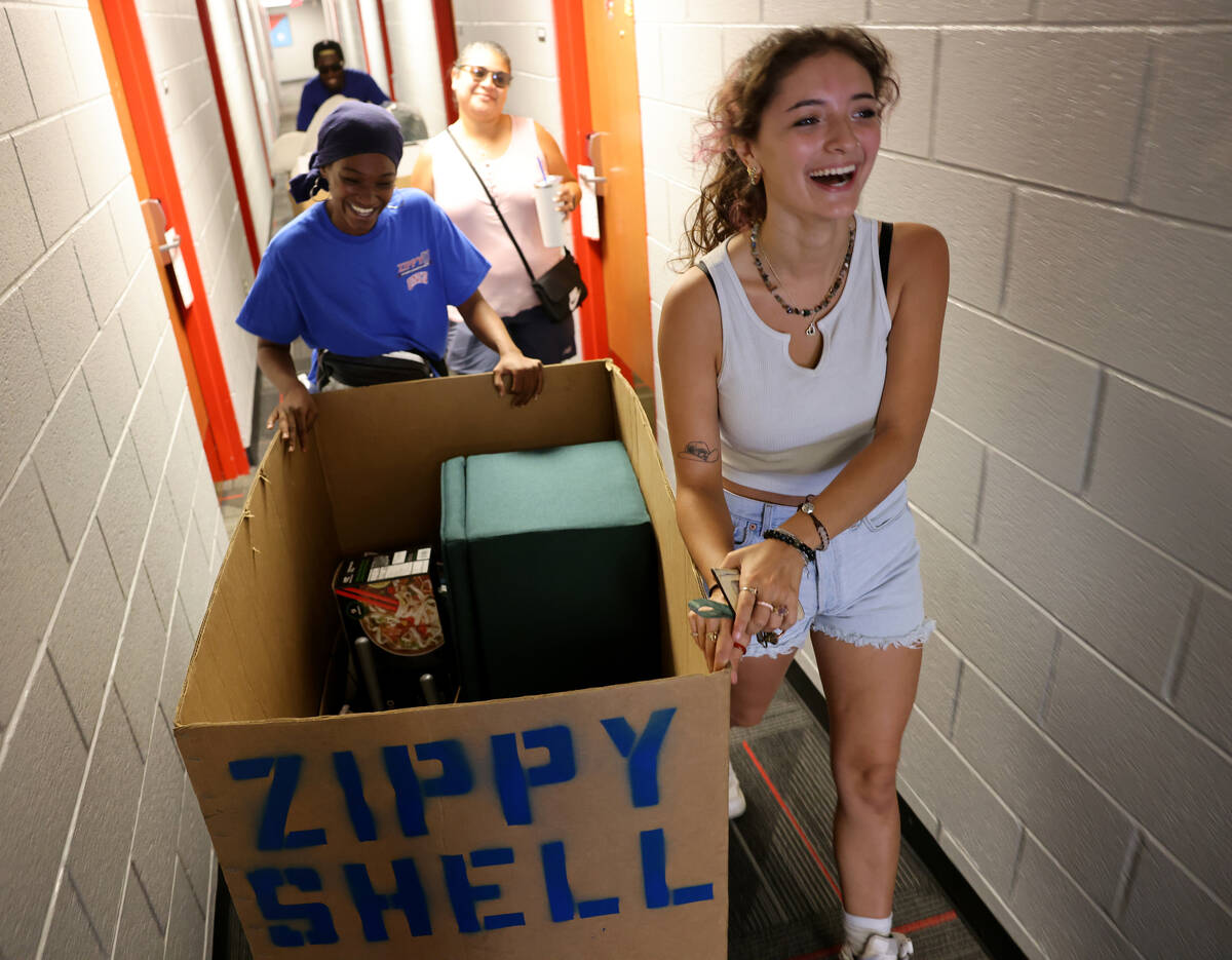 Student Viviana Dolfin rolls her possessions with mover Kieishia McNeal during dorm move-in day ...