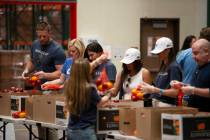 NFL's J.J. Watt, far left, helps pack bags of fruit with volunteers from Wheels Up at the Three ...