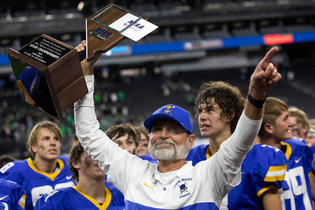 Moapa Valley coach Brent Lewis holds up his team's Class 3A football state championship trophy ...