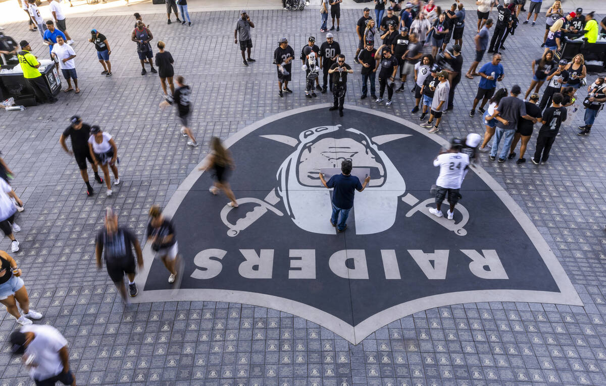 Raiders fans stop for photos as others stream by outside the entrance before the first half of ...