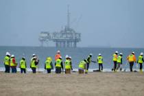 FILE - Workers in protective suits continue to clean the contaminated beach with a platform in ...