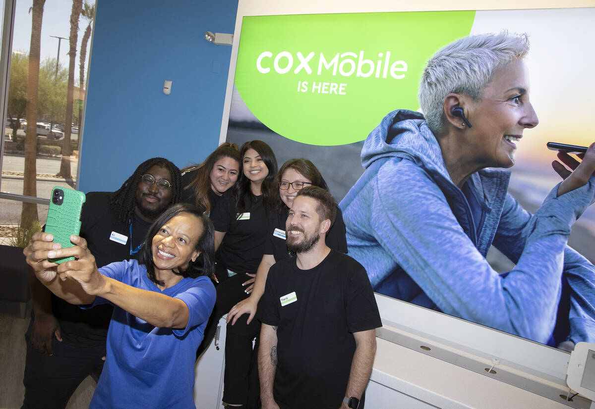Janet Uthman, market vice-president at Cox Communications, takes a selfie with retail employees ...
