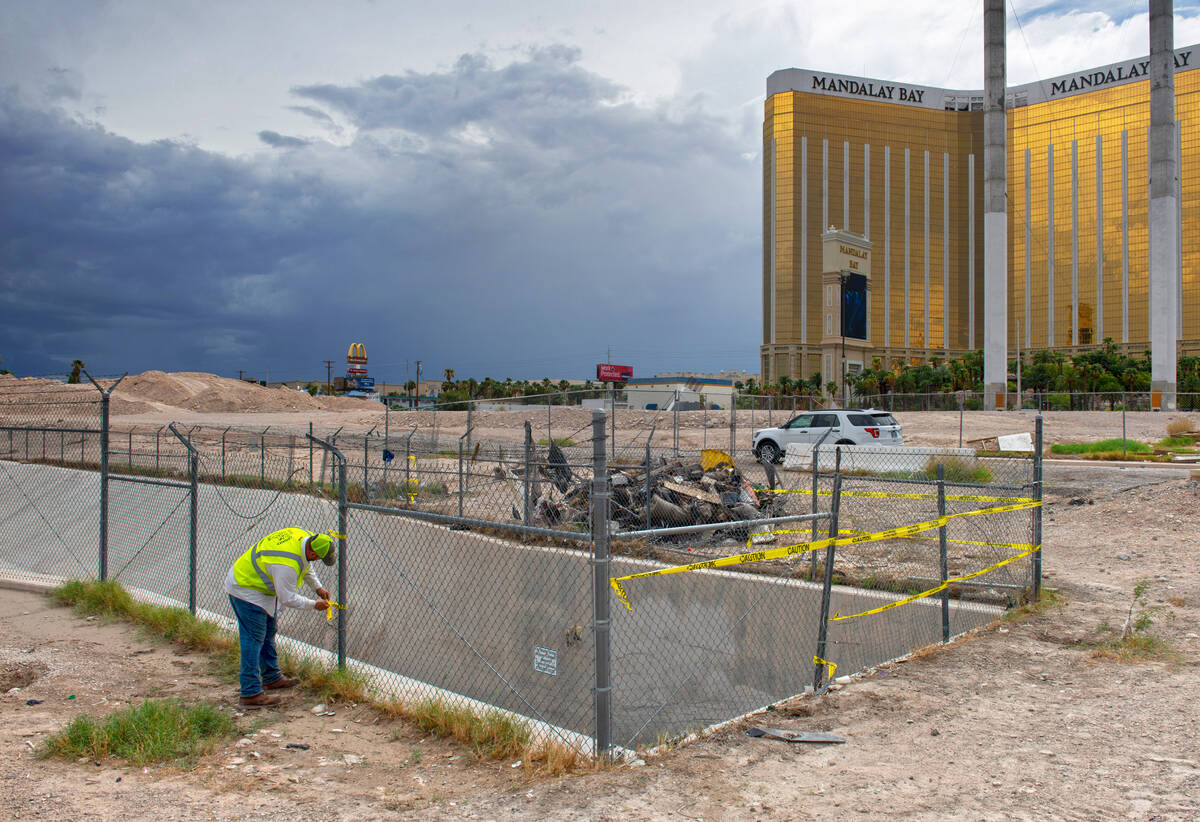 A Clark County Public Works employee tapes off a fence around a flood channel where two people ...