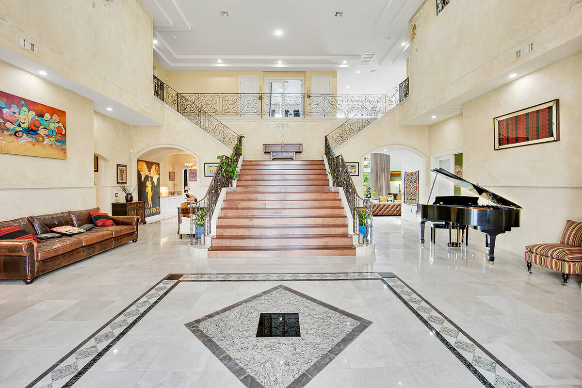 The grand staircase, anchored by an ornate iron handrail, splits mid-height with two staircases ...