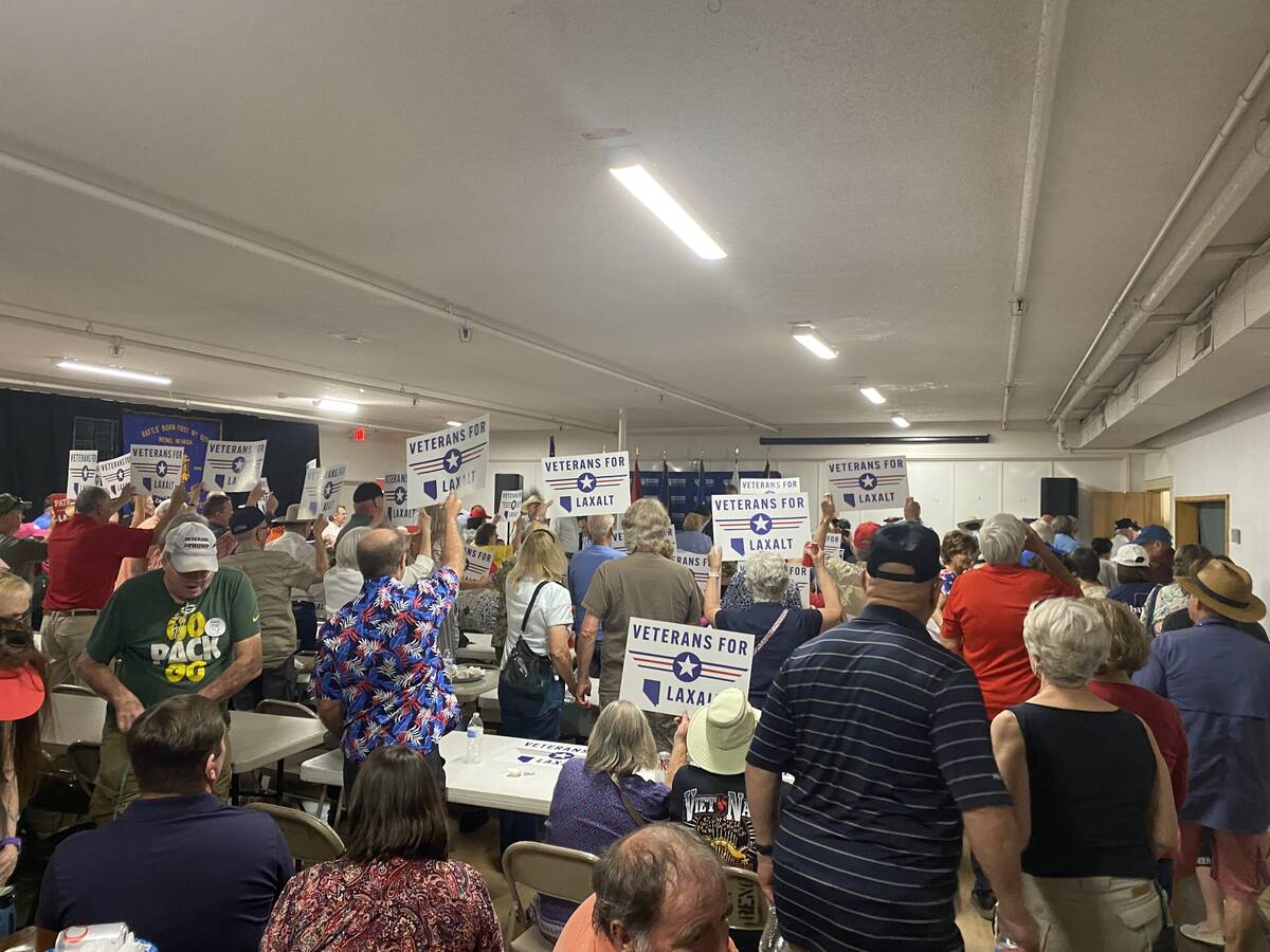 Attendees at a veterans' event in Reno hold up signs that read "Veterans for Laxalt" on Sept. 1 ...