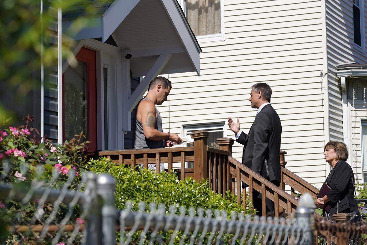 Dan Sideris, center, talks with a resident on a front porch accompanied by his wife, Carrie Sid ...