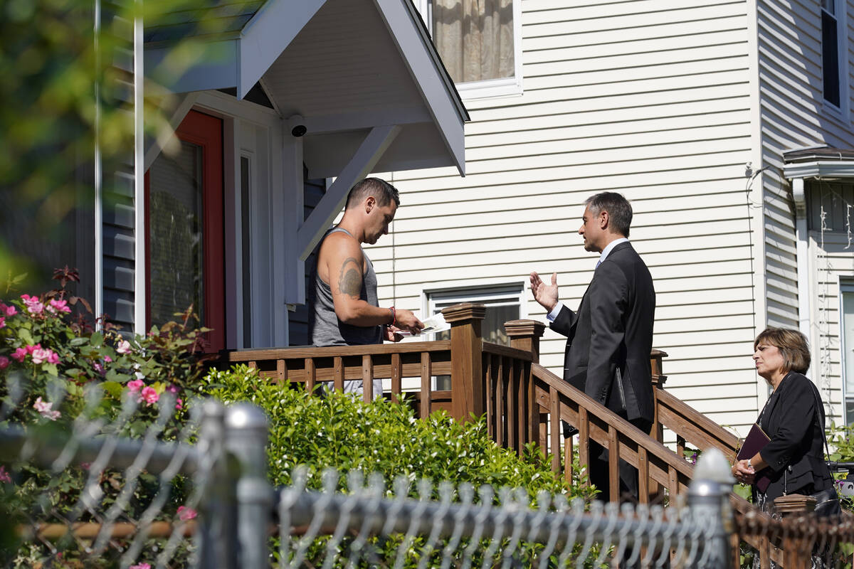 Dan Sideris, center, talks with a resident on a front porch accompanied by his wife, Carrie Sid ...