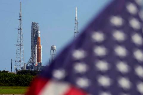 An American flag flies in the breeze as NASA's new moon rocket sits on Launch Pad 39-B after be ...