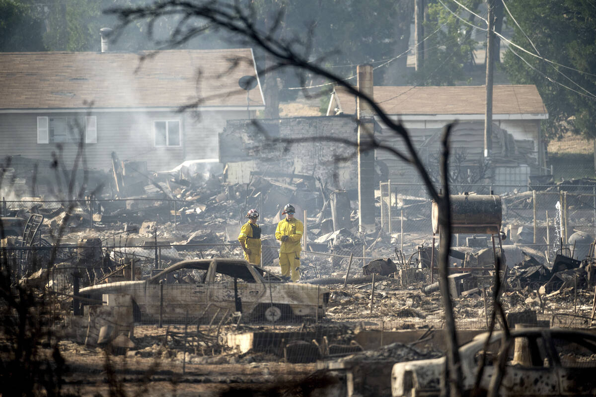 Firefighters survey homes on Wakefield Avenue destroyed by the Mill Fire on Saturday, Sept. 3, ...
