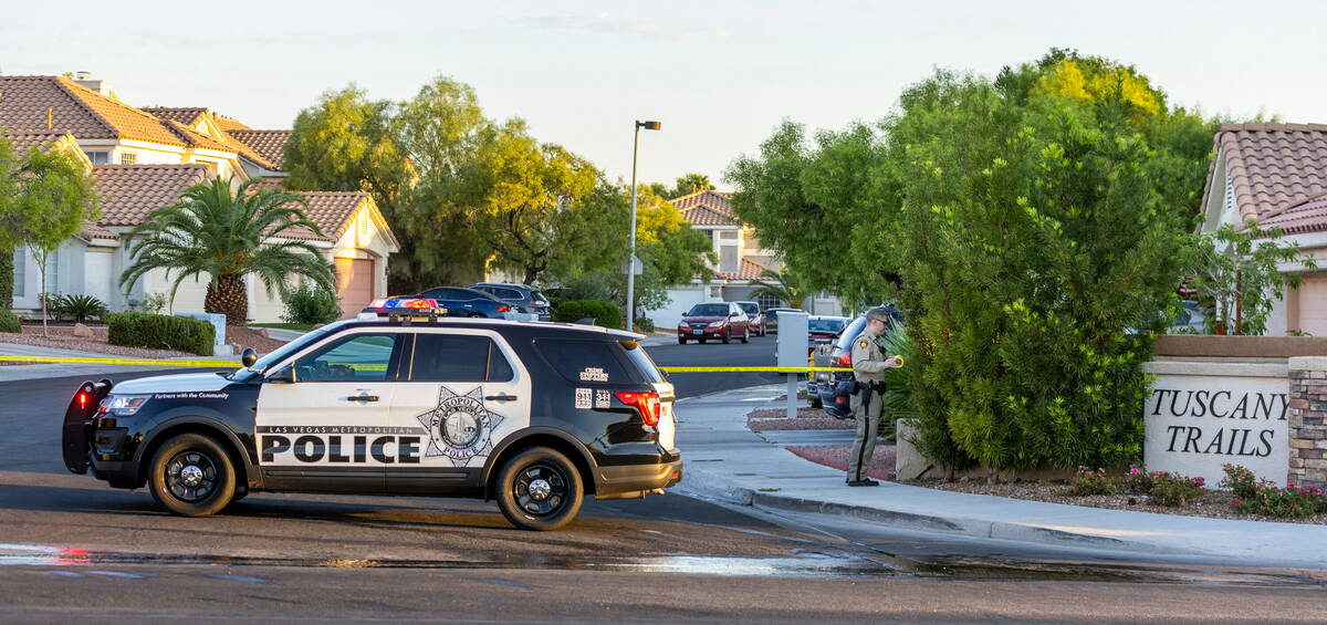 A Las Vegas police officer blocks off the entrance to the Tuscany Trails neighborhood and the h ...