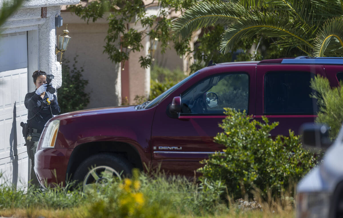 A Las Vegas police crime scene investigator takes photos of a vehicle outside the home of Rober ...