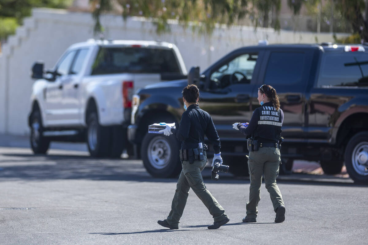 Las Vegas police crime scene investigators walk in the street outside the home of Robert Telles ...