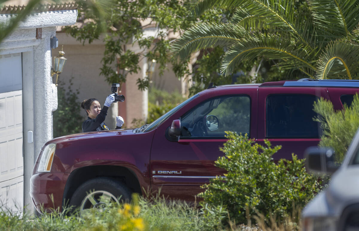 A Metro Crime Scene Investigator takes photos of a suspect vehicle outside the home of Robert T ...