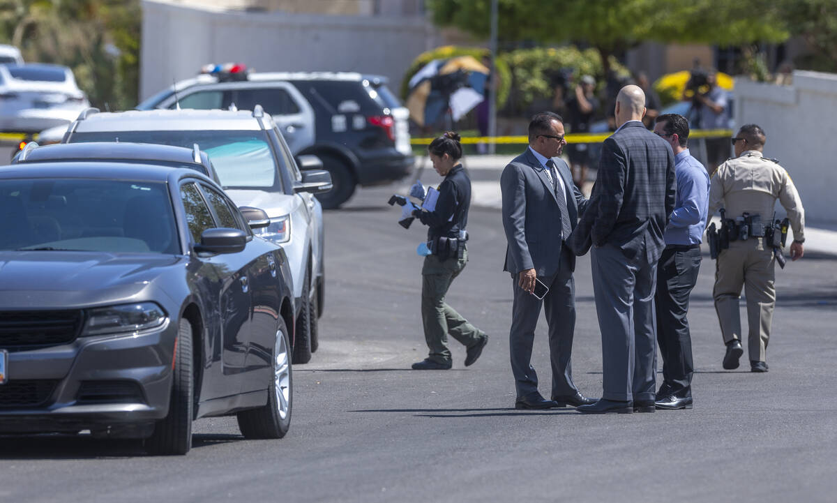 A Las Vegas police crime scene investigator takes photos as other officers talk in the street o ...