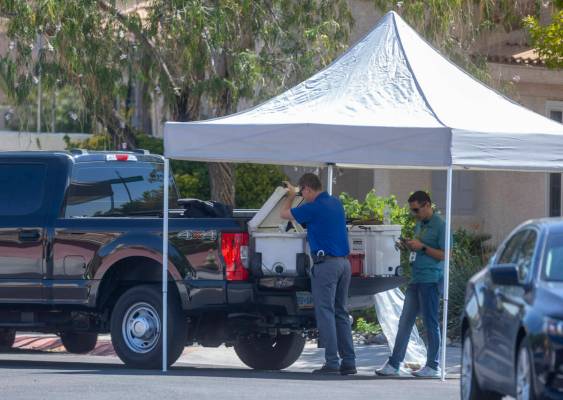 Las Vegas police homicide detectives work beneath a tent in the street outside the home of Robe ...