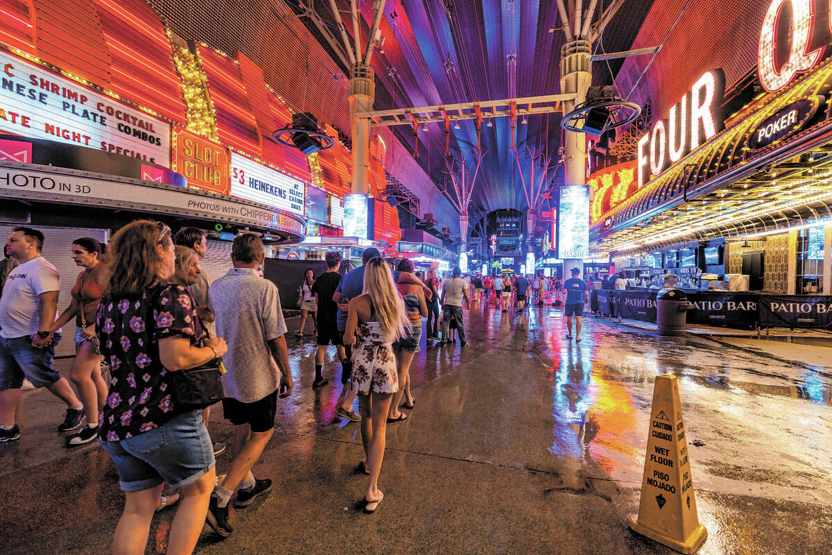 FILE - People navigate the rainy walkways as some power is out at the Fremont Street Experience ...