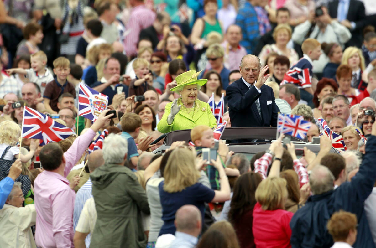 Britain's Queen Elizabeth II and Prince Philip wave to thousands of people in Stormont estate, ...