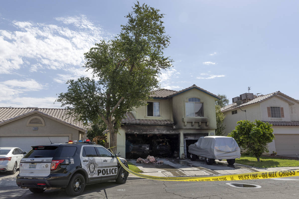 FILE - Metropolitan police remain at the scene of a house fire that was extinguished by fire cr ...