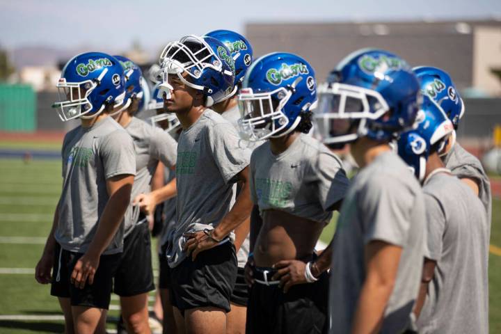 Players stand on the sideline during a football practice at Green Valley High School in Henders ...