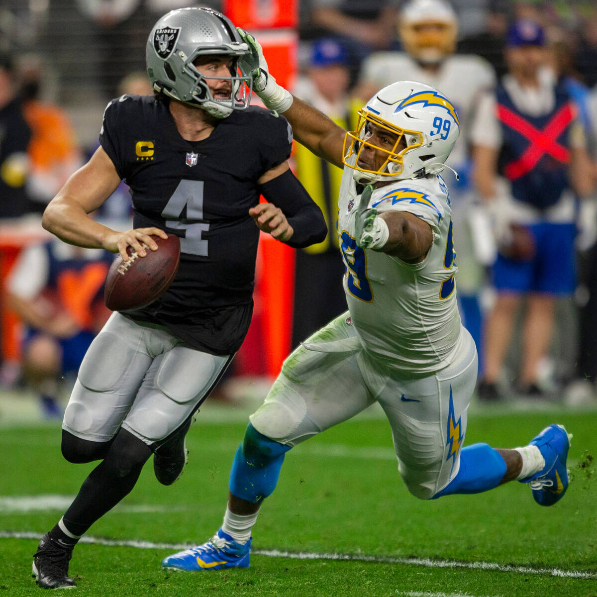 Raiders quarterback Derek Carr (4) scrambles to escape pressure from Los Angeles Chargers defen ...