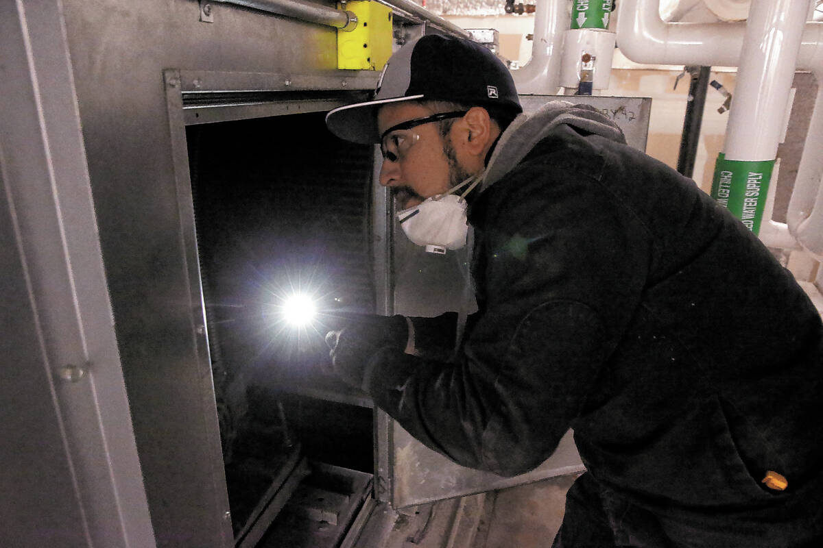 FILE - Clark County School District Building Engineer IV Juan Avila works on the heating, venti ...