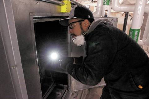 FILE - Clark County School District Building Engineer IV Juan Avila works on the heating, venti ...