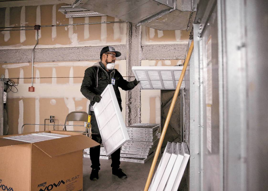 FILE - Clark County School District Building Engineer IV Juan Avila changes filters on the heat ...