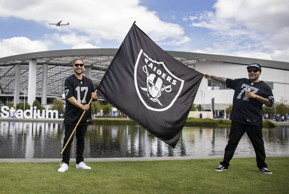 Raiders fans Andrew Lopez, left, and Lester Gonzalez hold up their team flag at SoFi Stadium be ...