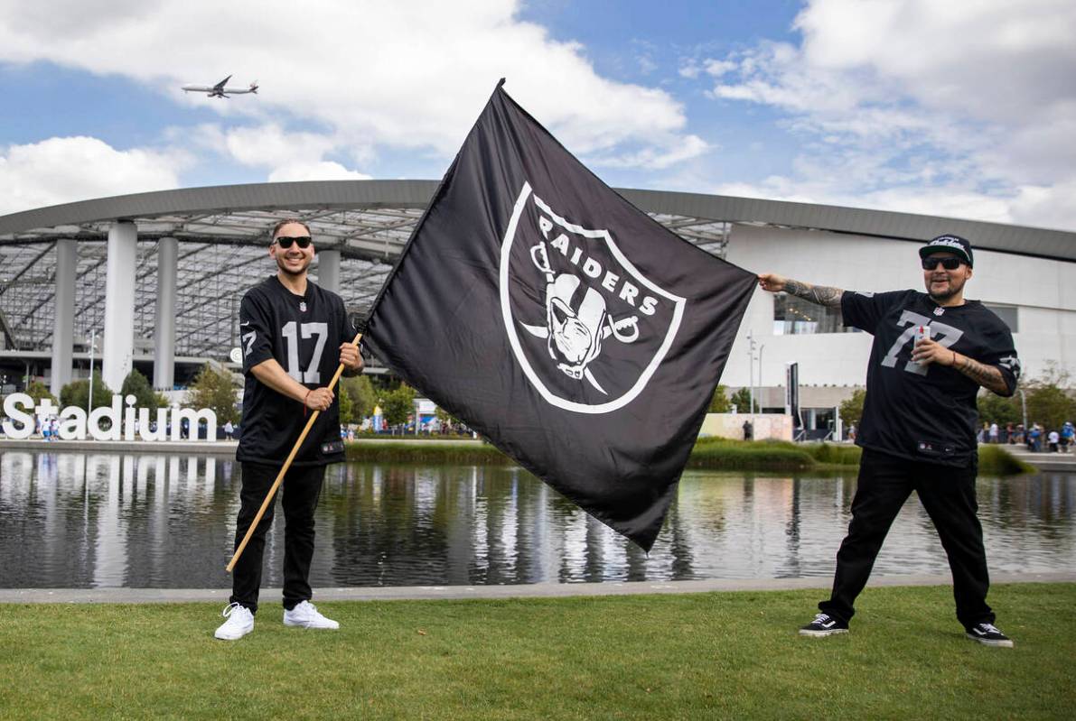 Raiders fans Andrew Lopez, left, and Lester Gonzalez hold up their team flag at SoFi Stadium be ...