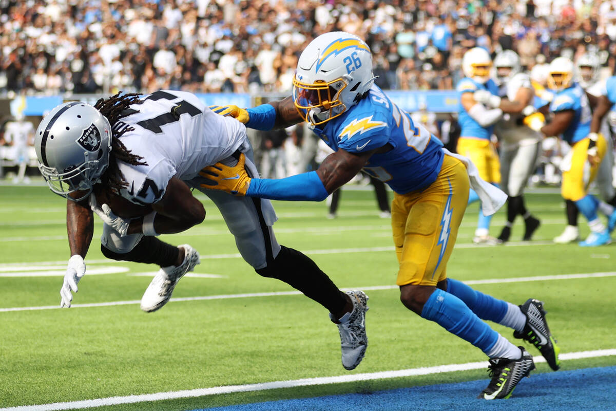 Raiders wide receiver Davante Adams (17) makes a catch for a touchdown under pressure from Los ...